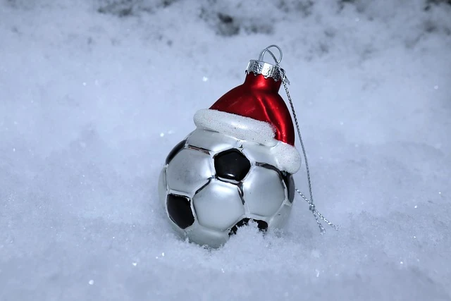 ein kleiner Anhänger für den Weihnachtsbaum in Form eines Fußballs mit Nikolausmütze im Schnee
